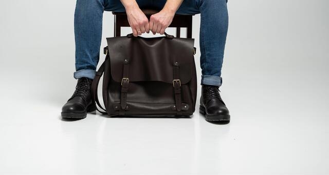 Classic black leather messenger bag featuring adjustable strap and laptop compartment.
