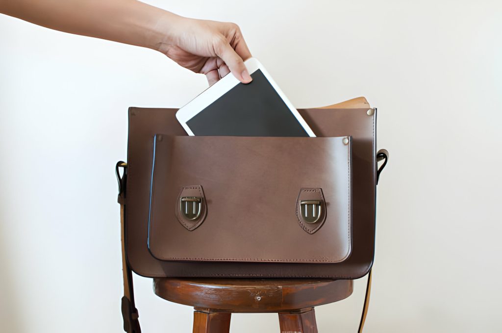 Leather backpack with laptop compartment against brick wall backdrop.